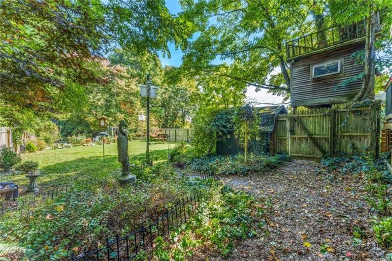 Fenced-in back yard with tree house