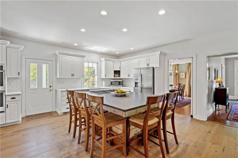 White cabinetry, wide plank flooring and stainless steel appliances are found in the kitchen.