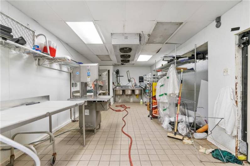 Butcher's prep area behind produce and meat display