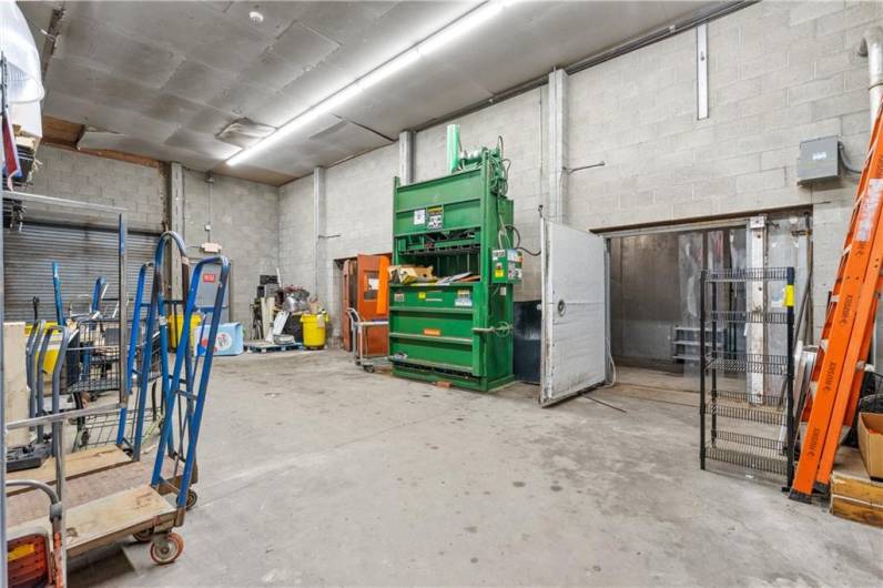 Back storage area with garage door for unloading trucks at parking lot level.  Trash compactor and walk in freezer