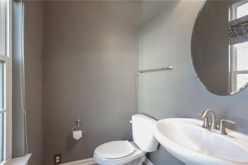 The main level powder room is tucked off the family room and features a bright window.