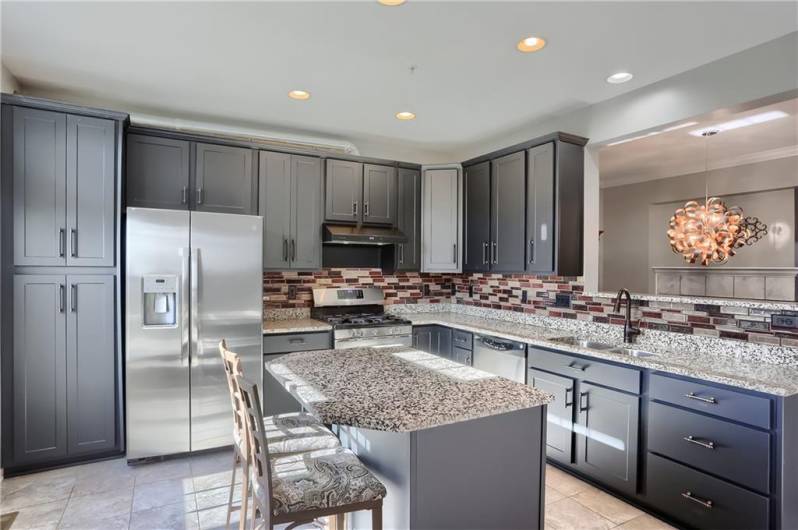 Endless granite counter tops, complemented with a custom backsplash, rest on modern toned cabinetry.