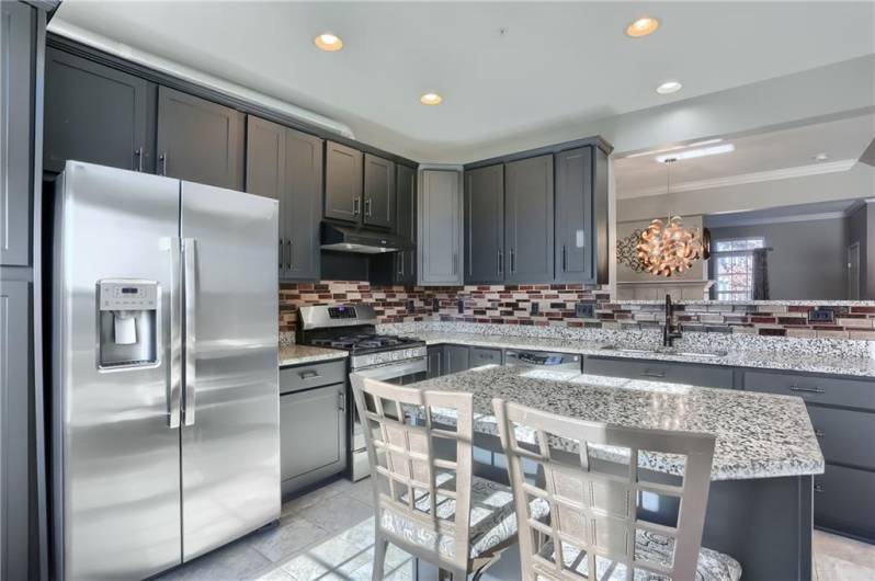 This kitchen will inspire the home chef. Stainless steel appliances include a gas stove with exteriorly vented range hood, granite counter tops, a custom backsplash and abundant, stylish cabinetry.