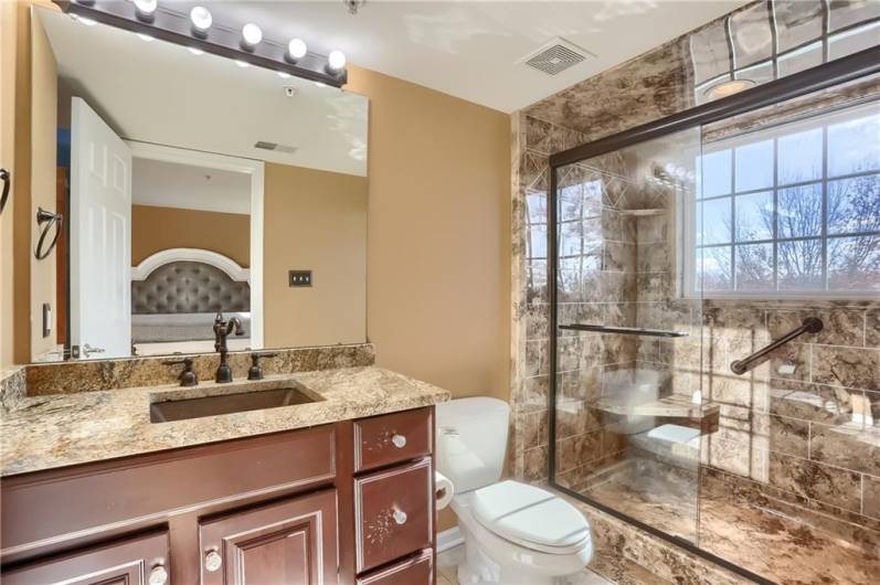 The new spa like primary bathroom features a granite topped vanity with a copper sink, stylish hardware and an oversized tile shower.