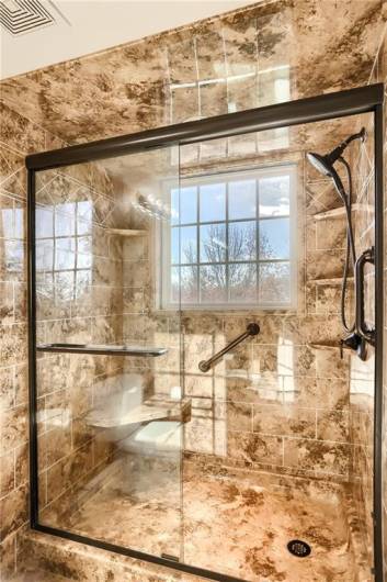 The custom tiled shower with bench seat and glass door is the perfect place to start or end your days.