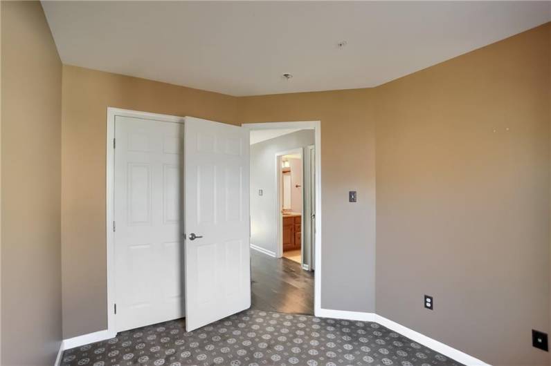 Guest bedroom with plush carpet and abundant storage.