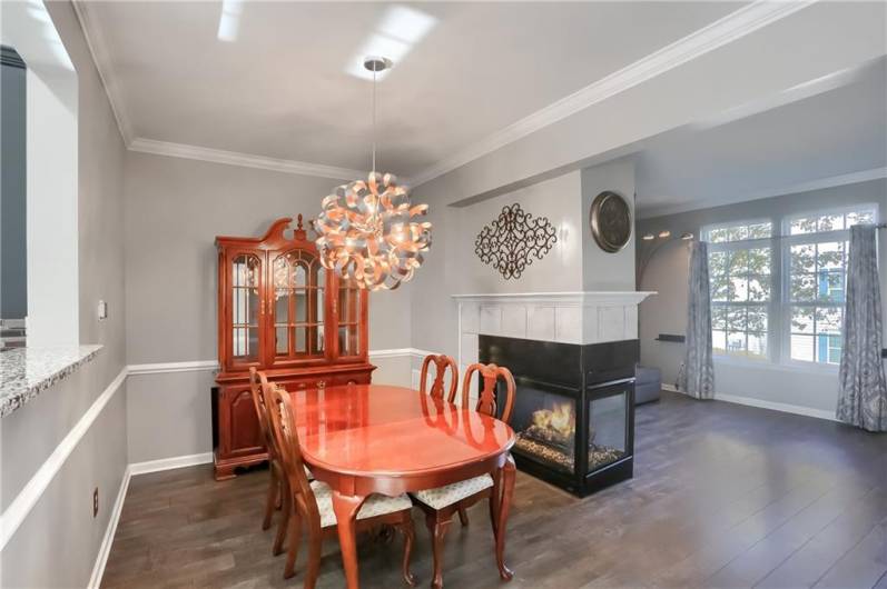 A spacious dining room features a stylish chandelier, modern low maintenance flooring, crown molding, a neutral tone and a chair rail.