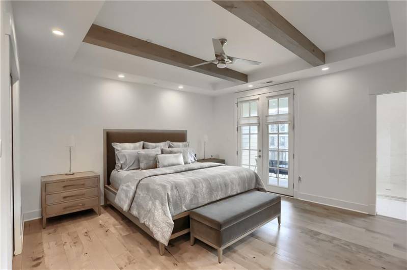 The primary bedroom features exposed beams, a trey ceiling, French door access to a deck and a spa like bathroom.