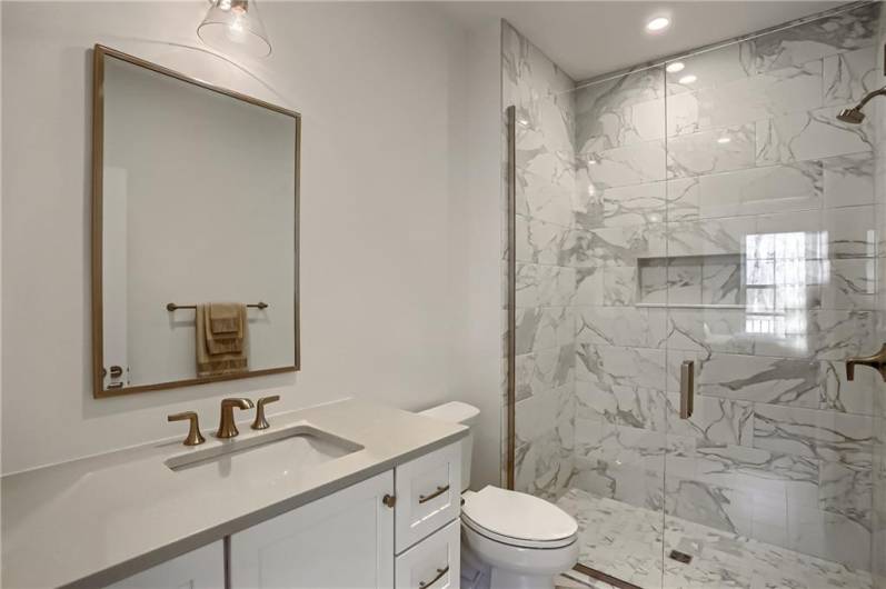 The high end ensuite bathroom features a modern vanity and tile shower with glass door.