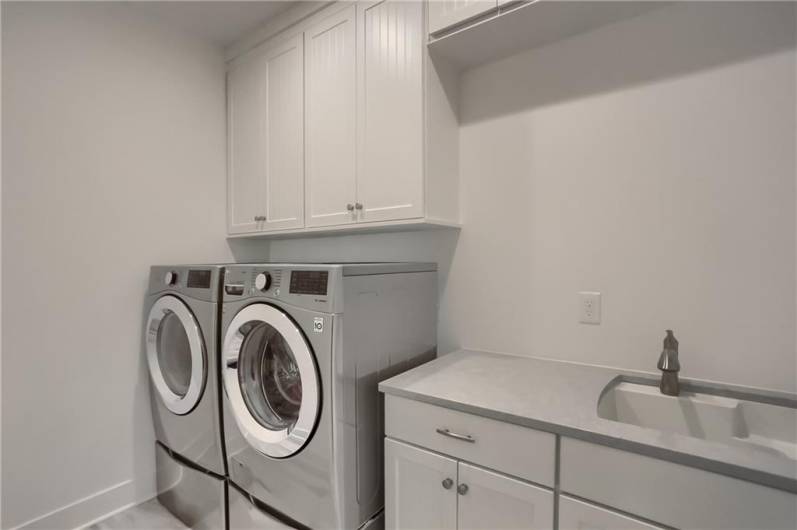 Even the laundry room features luxurious finishes; a large vanity with laundry sink, built in cabinetry and tile flooring.