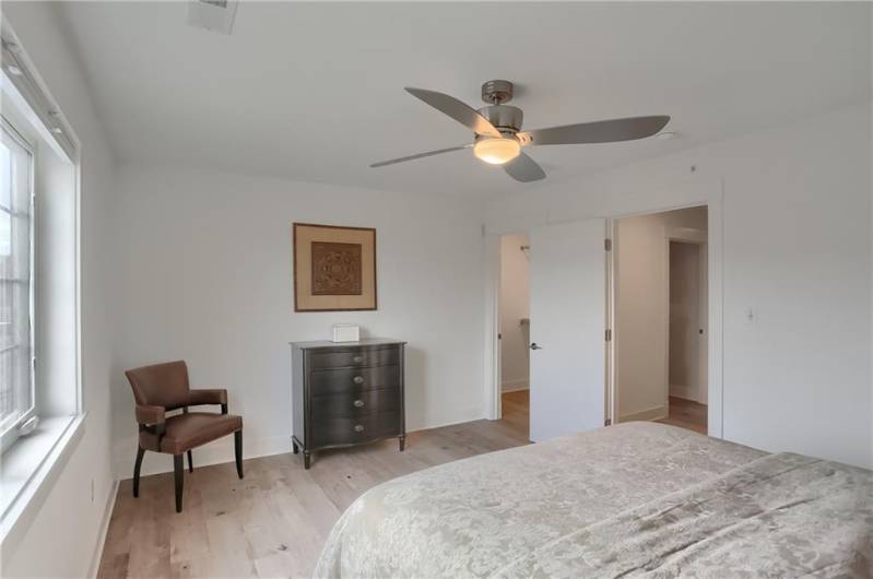 This guest bedroom has a large walk in closet, bright windows and a ceiling fan.