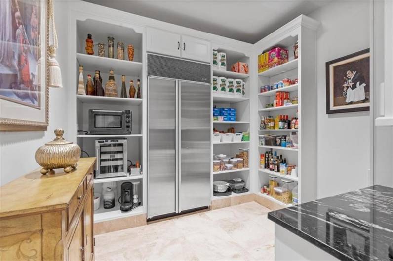 The expansive walk-in pantry features custom cabinetry, shelving and desk area with granite counter top, Travertine floors, and second. Sub-Zero refrigerator