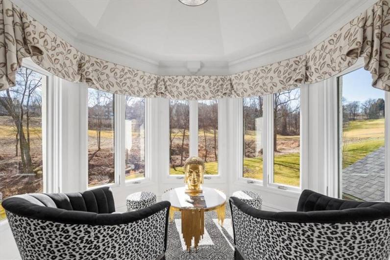 lanked by floor to ceiling windows with custom window treatments and electronic blinds offering breathtaking panoramic views of the golf course and nature area.