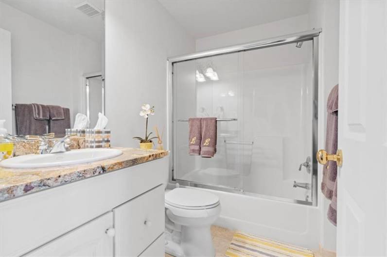 Private en-suite bath hosting a spacious vanity with granite counter-top, tile flooring, glass enclosed full tub & shower.