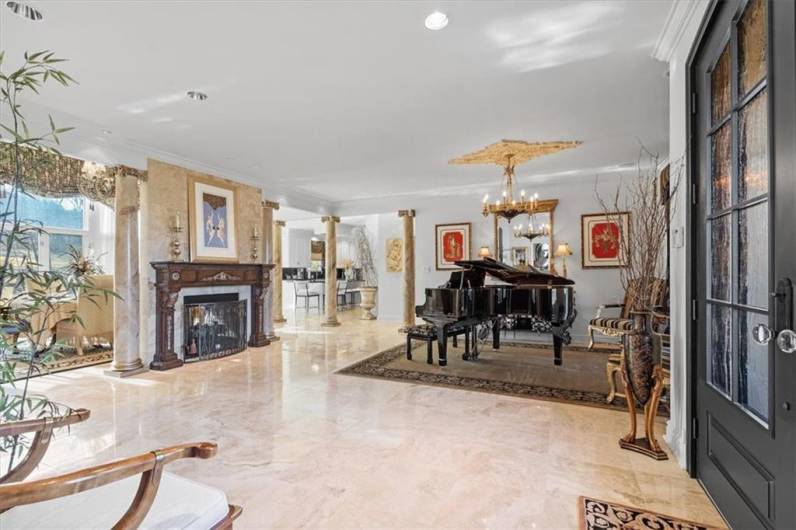 The inviting open floor plan is highlighted by crown moldings, Travertine floors, elegant columns, two-sided gas fireplace with a stately wood mantel and Travertine accents.