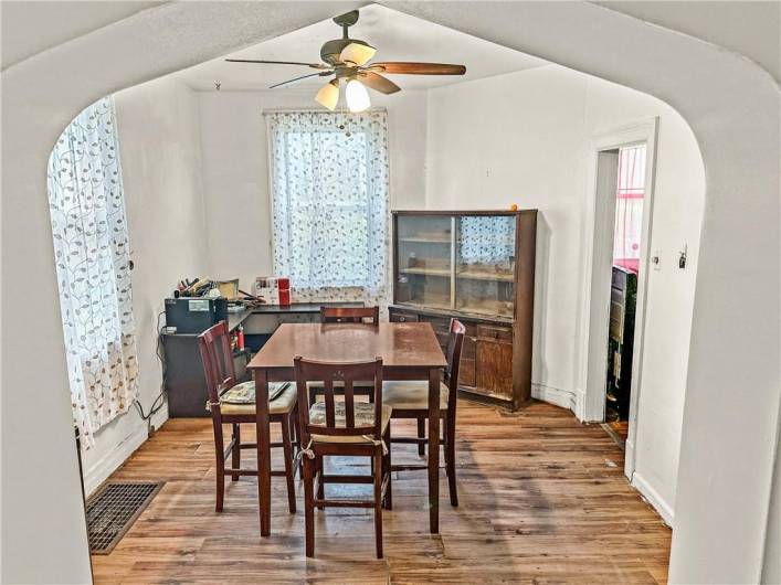 Spacious Dining Room with high ceilings, ceiling fan, original doorway archways, laminate flooring, and excellent natural light!