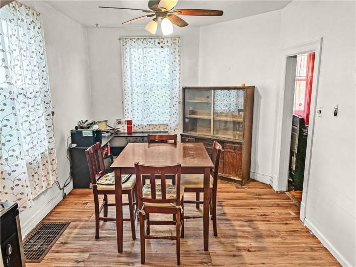 Spacious Dining Room with high ceilings, ceiling fan, original doorway archways, laminate flooring, and excellent natural light!