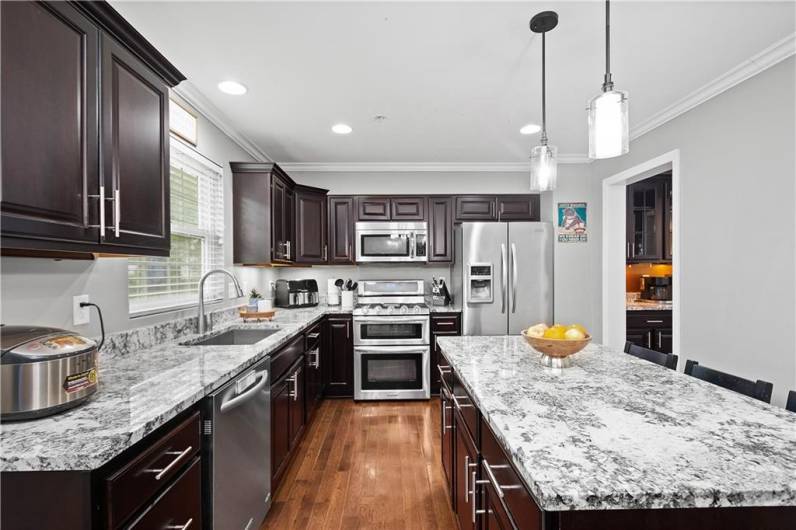 Stunning chef's kitchen with granite countertops, under cabinet lighting, pendant lighting, and hardwood flooring!