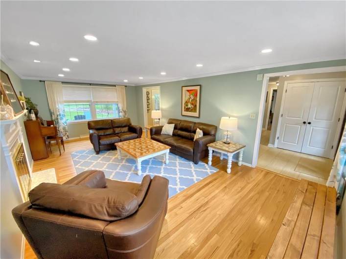 Large living room with hardwood floors, crown moldings, and recessed lights.