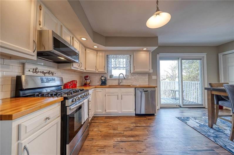 Heart of the home is this comfortable kitchen with butcher-block counters, stainless appliances, LVP flooring, and large pantry to the right. Sliding door leads to deck - stairs down to private patio and treelined backyard.