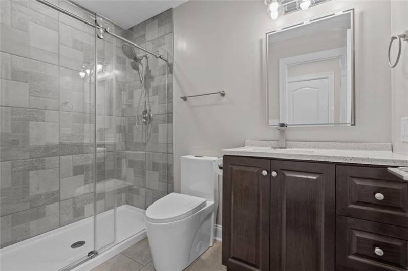 Full Bathroom #3 of 4. First Floor Half Bath has been expanded to Full Bath housing Ceramic Tile Shower, New Vanity, Lighting, and Plumbing