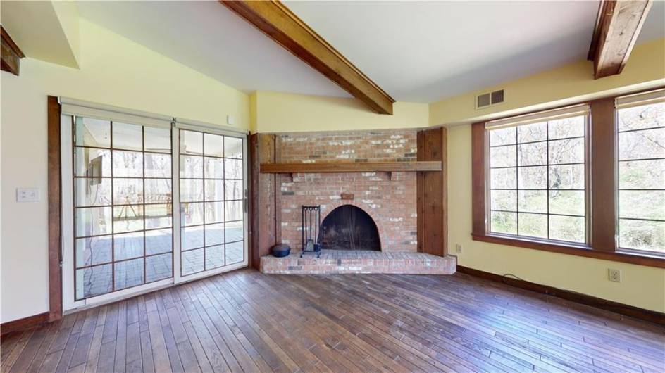 Beside the brick fireplace is a sliding glass door that leads to a covered patio.