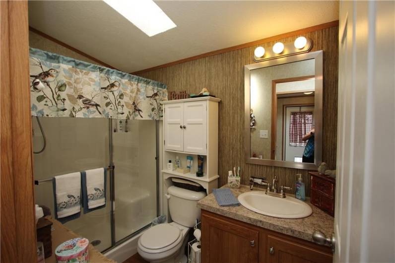 Shower Stall w/ 2 Seats in Full Bathroom boasting a Skylight! Also included is the Medicine Cabinet Furniture behind commode and also a linen towel storage