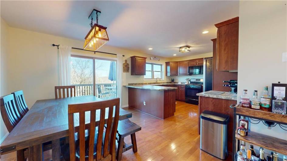 Step into a seamless blend of functionality and style with this open-concept kitchen and dining area, featuring sleek appliances, hardwood floors, and a charming dining area. Step out onto the deck from the dining area.
