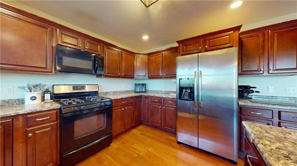 This kitchen boasts rich wooden cabinetry and sleek stainless-steel appliances, set against warm hardwood flooring.