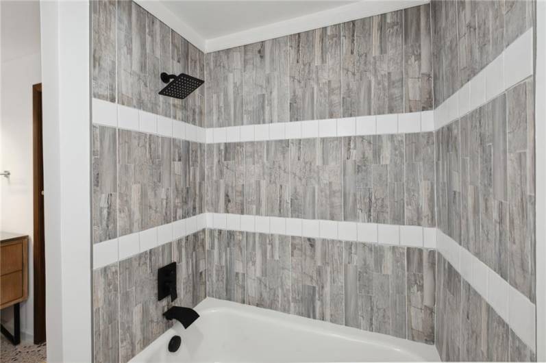 The completely renovated upstairs bath features beautiful, custom tile work and new fixtures.