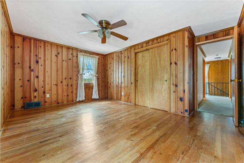 The upstairs bedroom has knotty pine paneling and hardwood floors