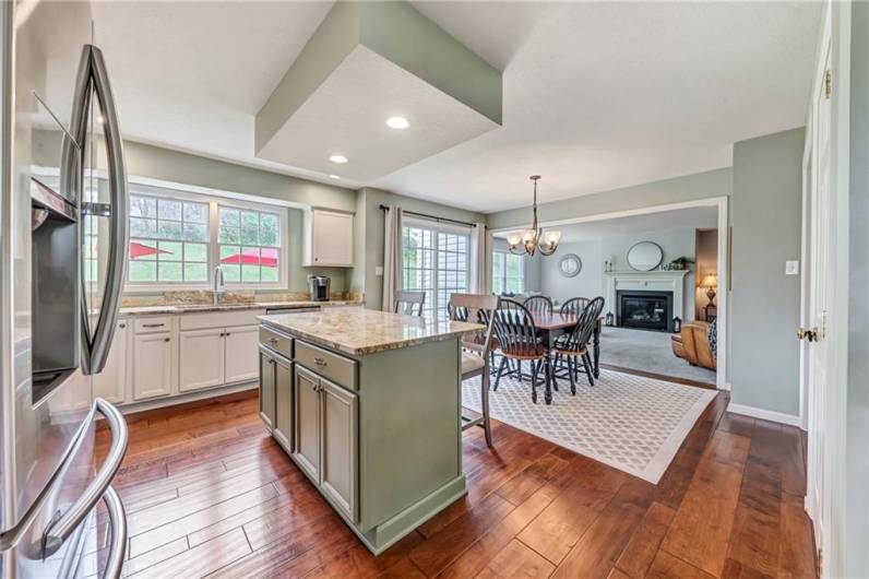 The spacious kitchen features newer hardwood flooring, a center island, and granite countertops.
