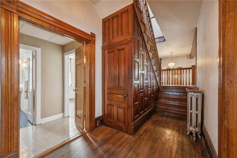 The back entry to the home, much like the front, welcomes you with its own chandelier and access to the Victorian era staircase. The door under the staircase is your coat closet, while the dual doors to your right are access to you kitchen, full bathroom and utility room/butler pantry.