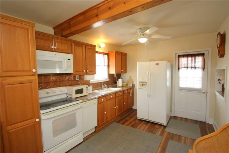 Gorgeous Eat-in Kitchen w/ Newer Flooring, Plenty of Wood Cabinets, Attractive Wood Beam in Ceiling, Ceiling Fan Light, Door to Backyard Pool & Party House, Beautiful Counter Tops boasting Tin Style Backsplash