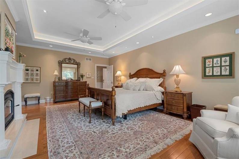 Master Bedroom with tray ceiling, accent lightig and gleaming hardwood flooring.