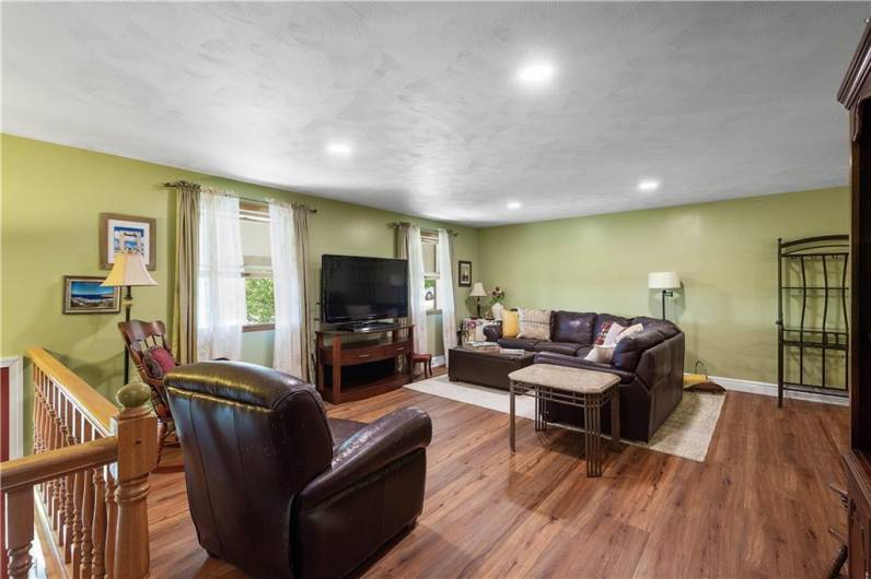 SPACIOUS LIVING ROOM WITH ADDED RECESSED LIGHTING AND EASY CARE LVT FLOORING.
