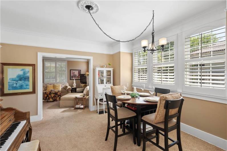 The dining room is light and bright with ample room for entertaining The wall of windows adorned with plantation shudders brightens the day, every day!