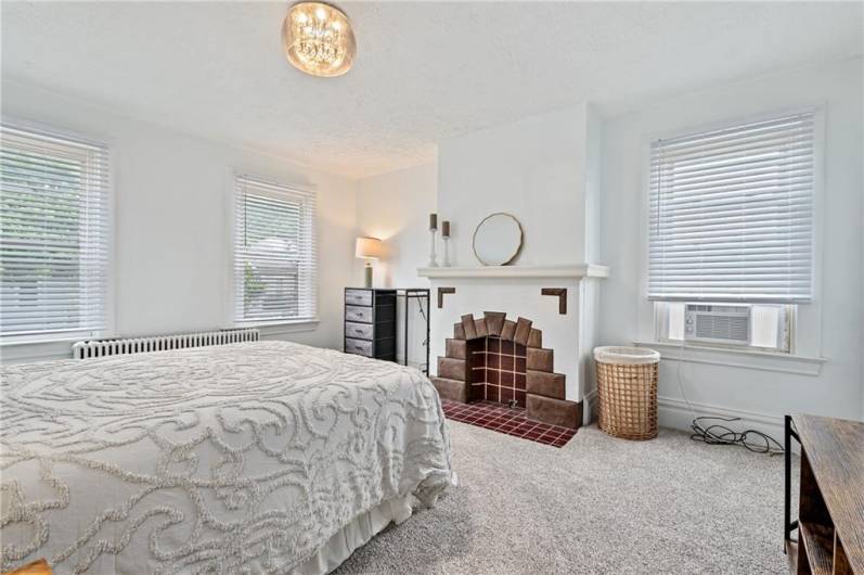 Very large, bright bedroom with decorative fireplace.