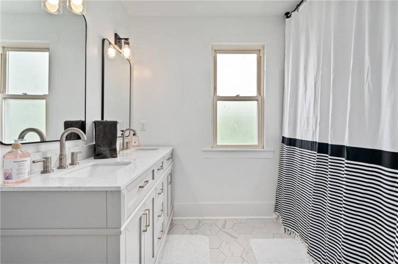 Spacious bathroom with double marble vanity and tub/shower combo.