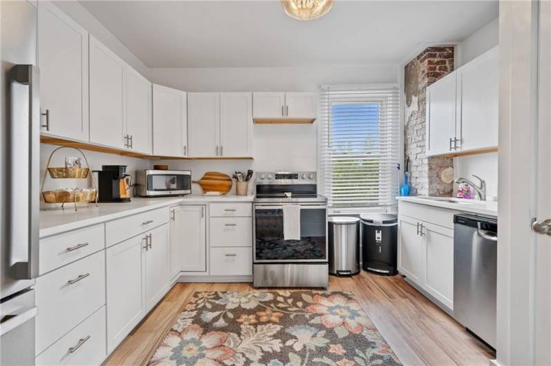 Large completely renovated kitchen with stainless steel appliances and exposed brick wall.