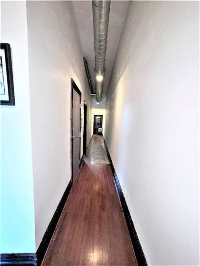 3rd floor hallway with entrance to the apartment to the left and long hallway with laundry area behind the door in the background.