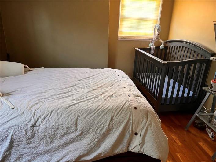 The secondary bedroom boasts a queen bed, crib, and armoire.