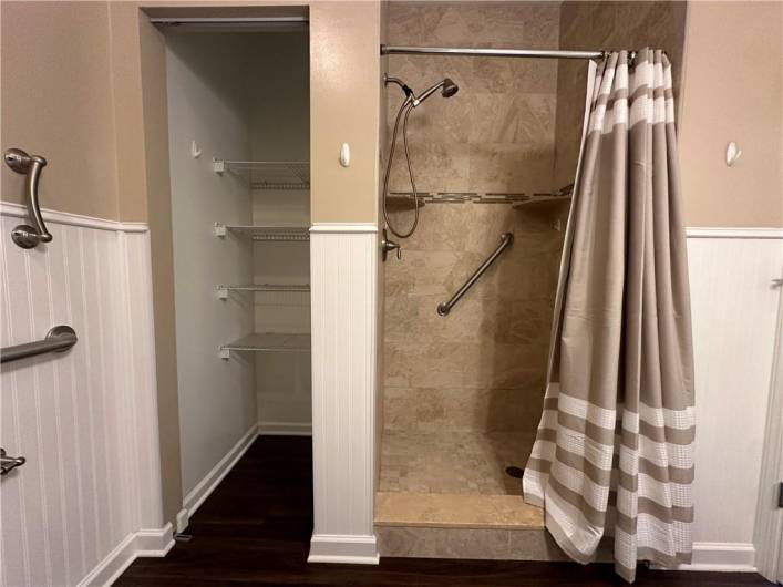 Updated 1st Floor Owner's Suite Bath offering white vanity with marble top, nickel faucet, mirrored medicine cabinet, LVT floor, ceramic shower, linen closet, beadboard half paneled walls.