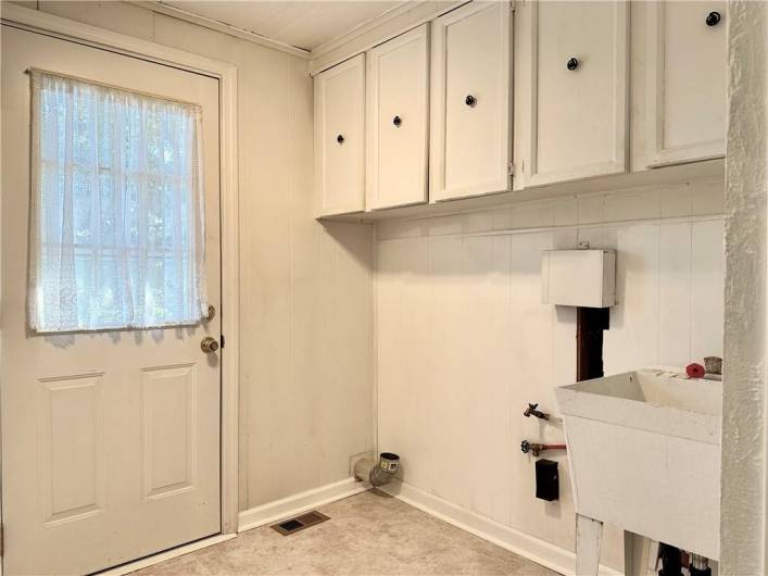 The back door gives entery into the mud room/laundry room.  There's more cabinets for storage and a utility sink in here, too.