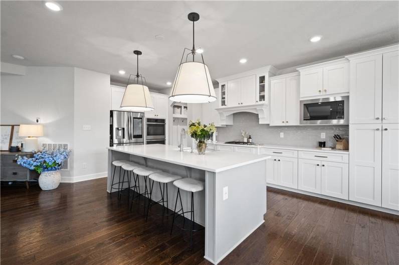 The luxurious Kitchen boasts a huge island, quartz countertops, modern white cabinetry, wall ovens & a beverage station.