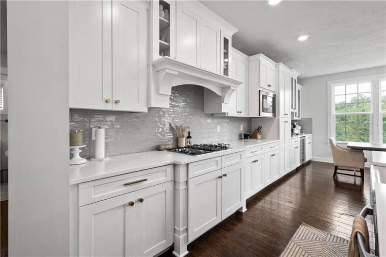 The luxurious Kitchen boasts a huge island, quartz countertops, modern white cabinetry, wall ovens & a beverage station.