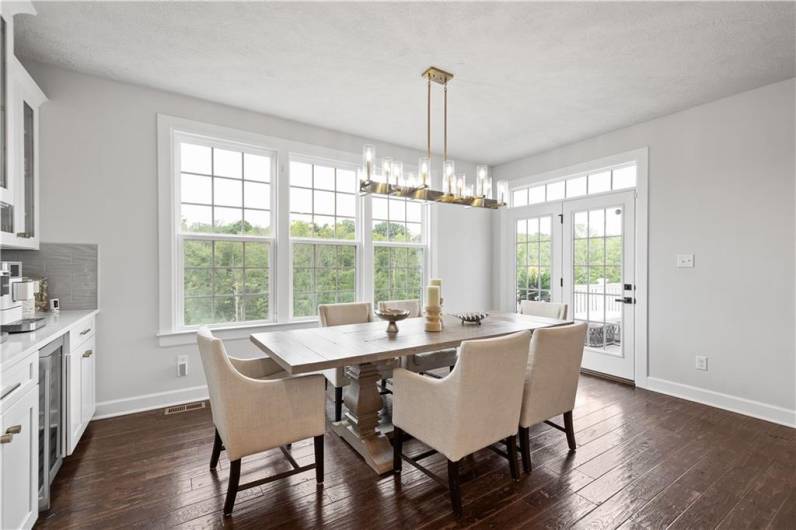 The Morning Room is surrounded by windows showcasing the wooded view. Doors lead out to the spacious deck.