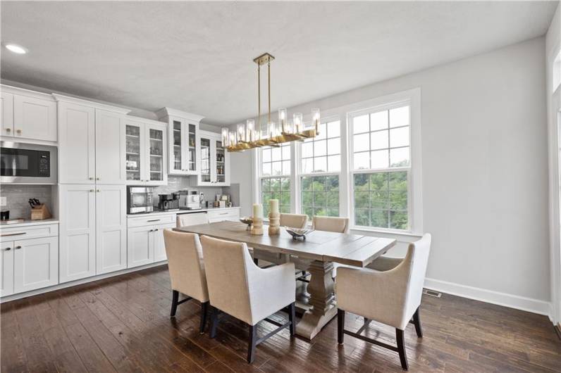 The Morning Room is surrounded by windows showcasing the wooded view. Doors lead out to the spacious deck.