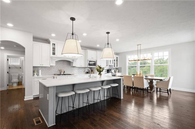 The luxurious Kitchen boasts a huge island, quartz countertops, modern white cabinetry, wall ovens & a beverage station.