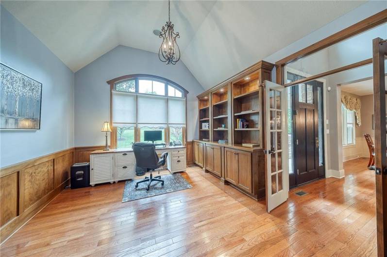 Den with built in bookcases and cabinets, hardwood floors, wainscotting.